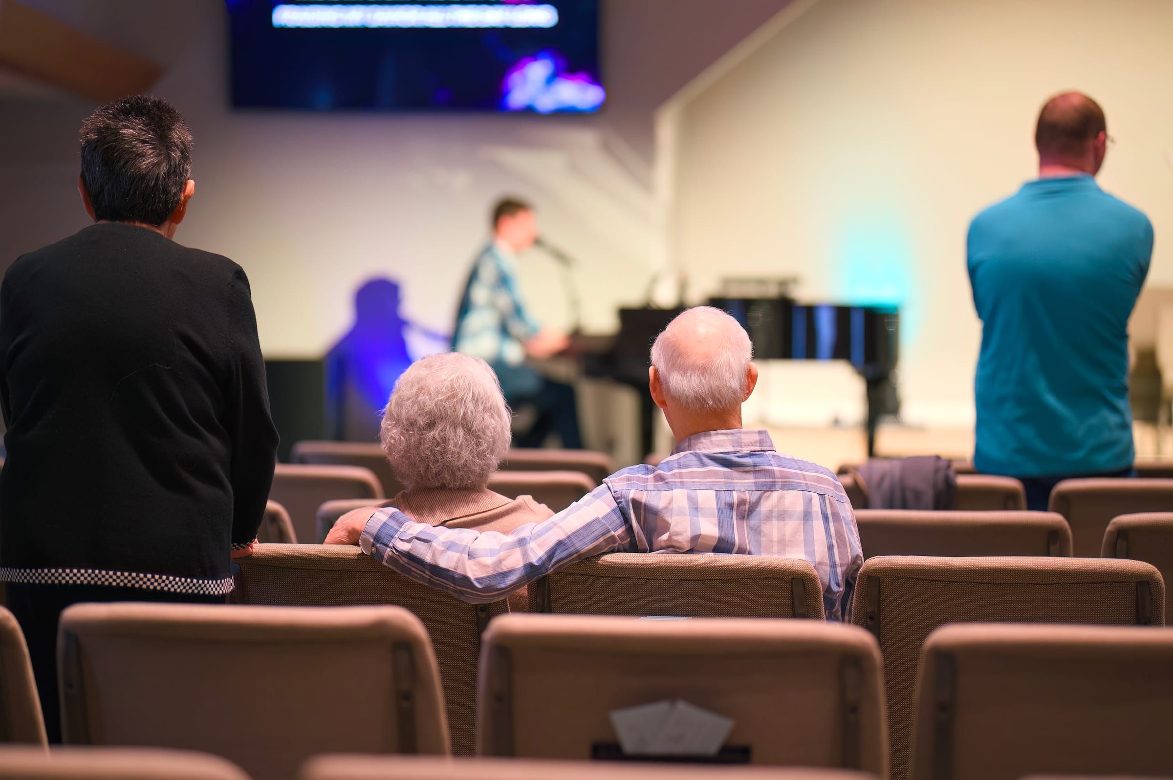 The congregation standing together during a worship gathering at Lucy Baptist Church, an elderly couple in the foreground.