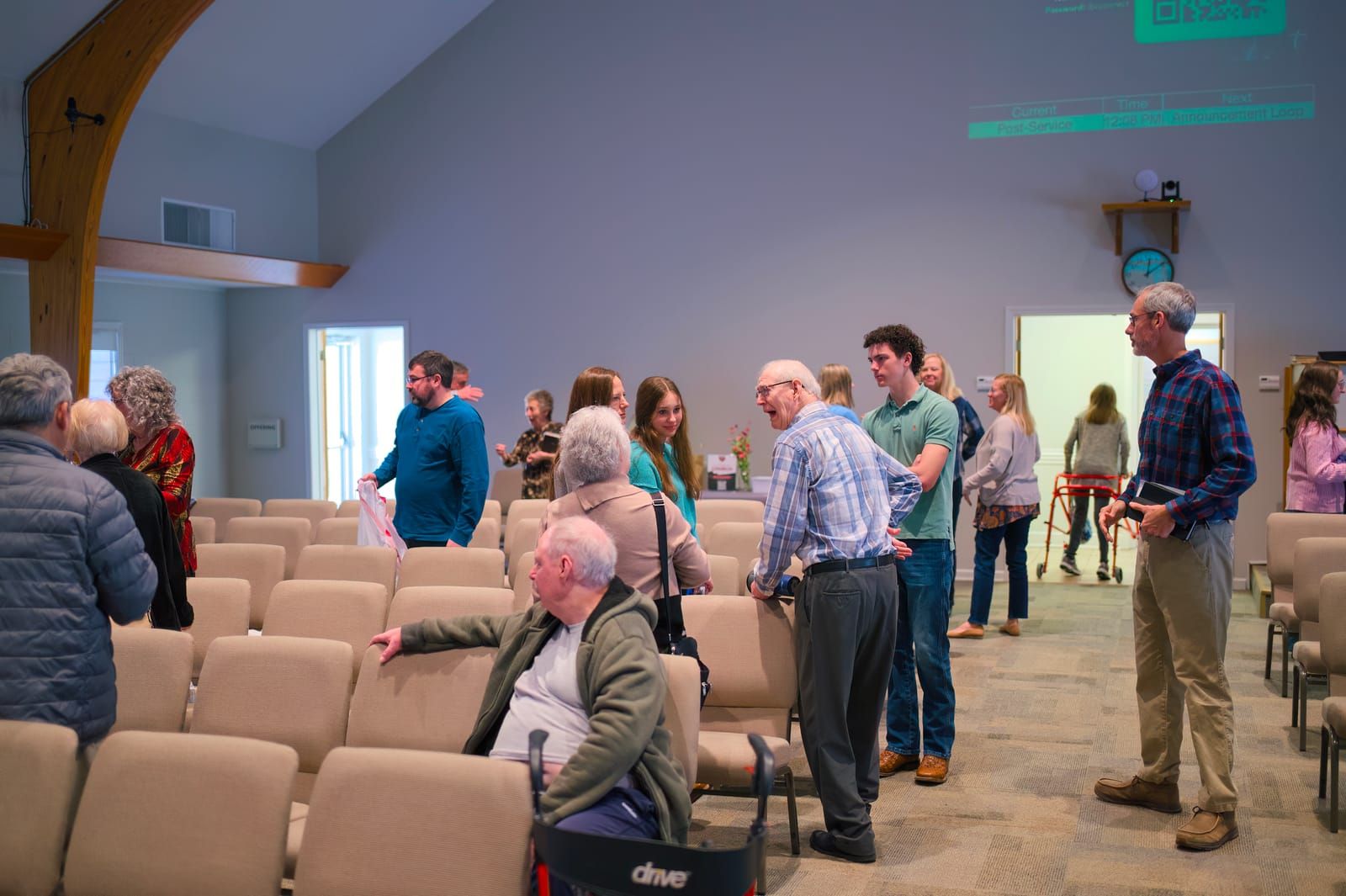 Members standing and talking together among the worship center chairs after a Sunday service at Lucy Baptist Church.