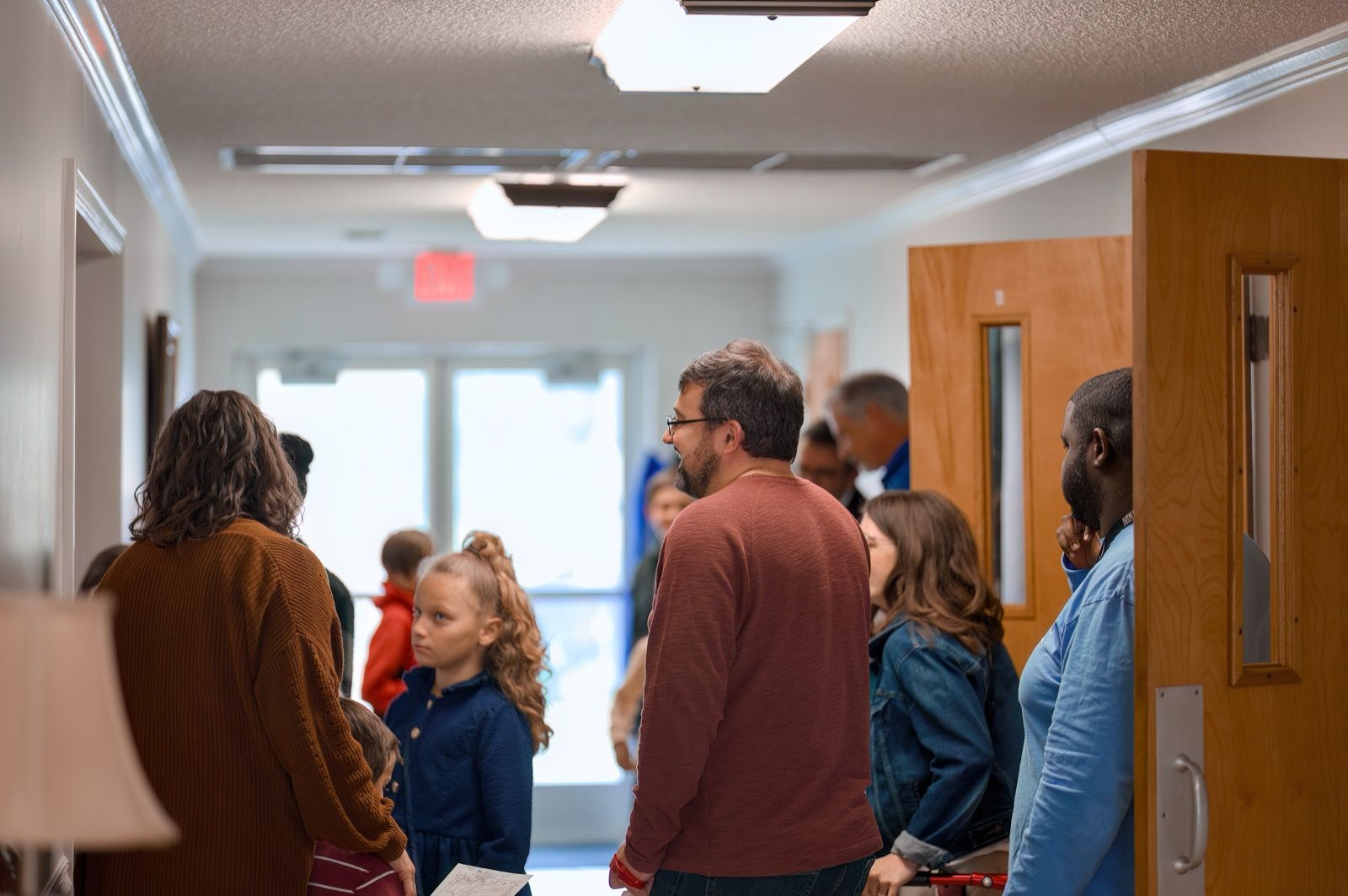 Members and families gathering in the Lucy Baptist Church lobby by the glass front doors before a Sunday gathering.
