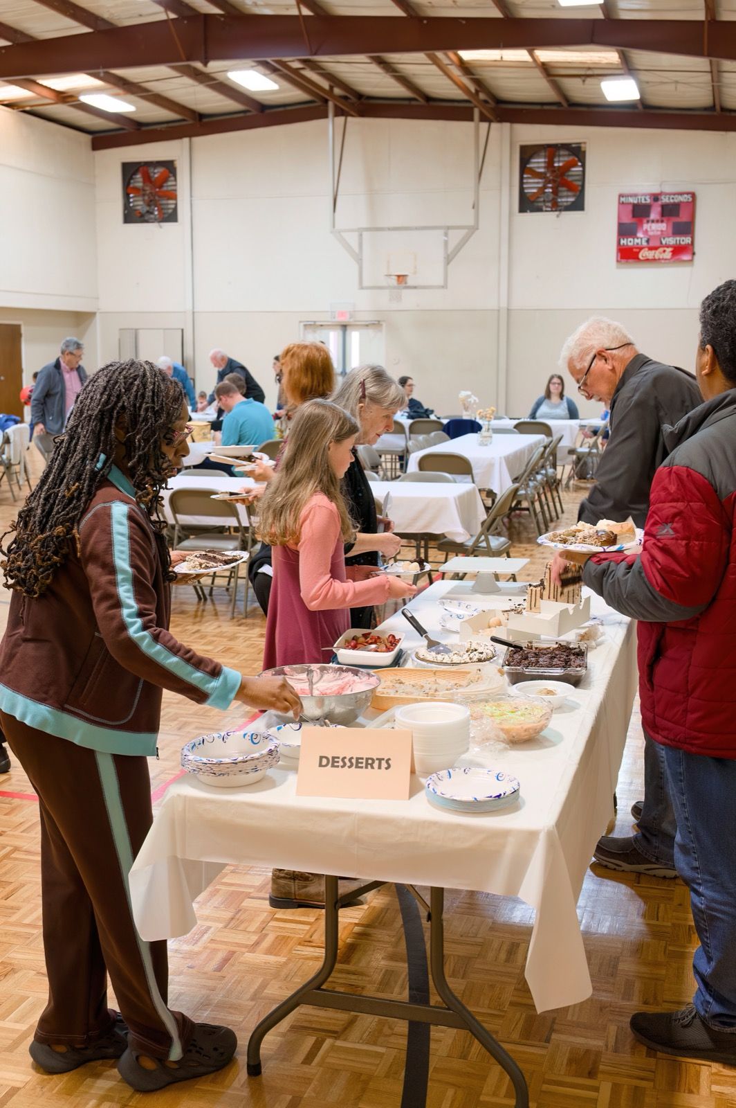 A girl choosing a treat at the dessert table during a church fellowship meal in the Lucy Baptist gym.